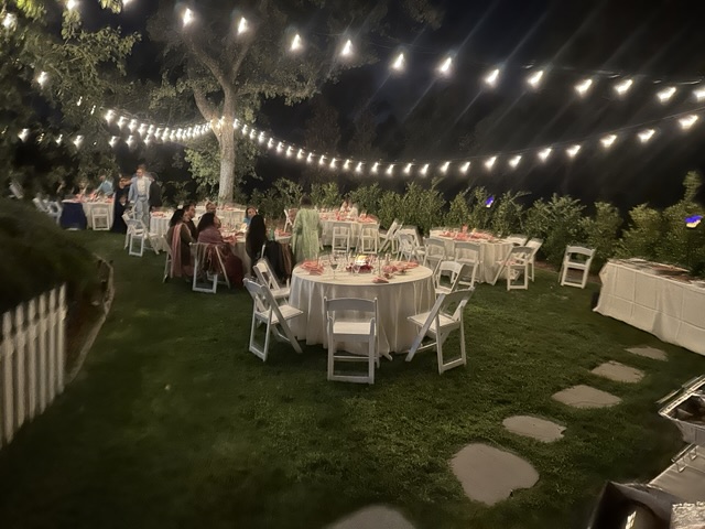 Garden celebration with round dining tables and overhead string lights