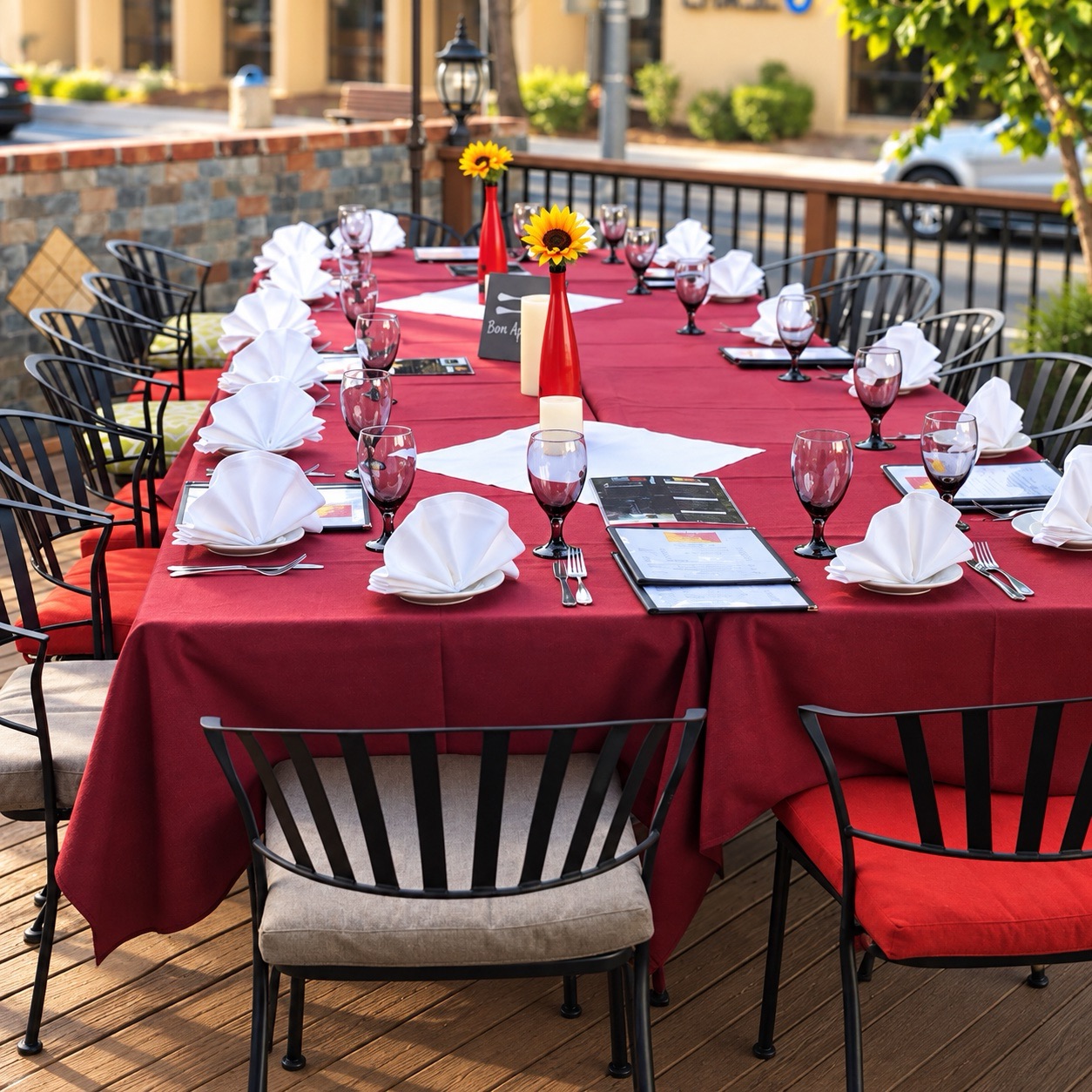 Patio table set with red linens and sunflowers for a group at Sicilia In Bocca