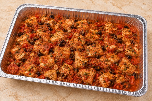 Swordfish Puttanesca served in a party tray