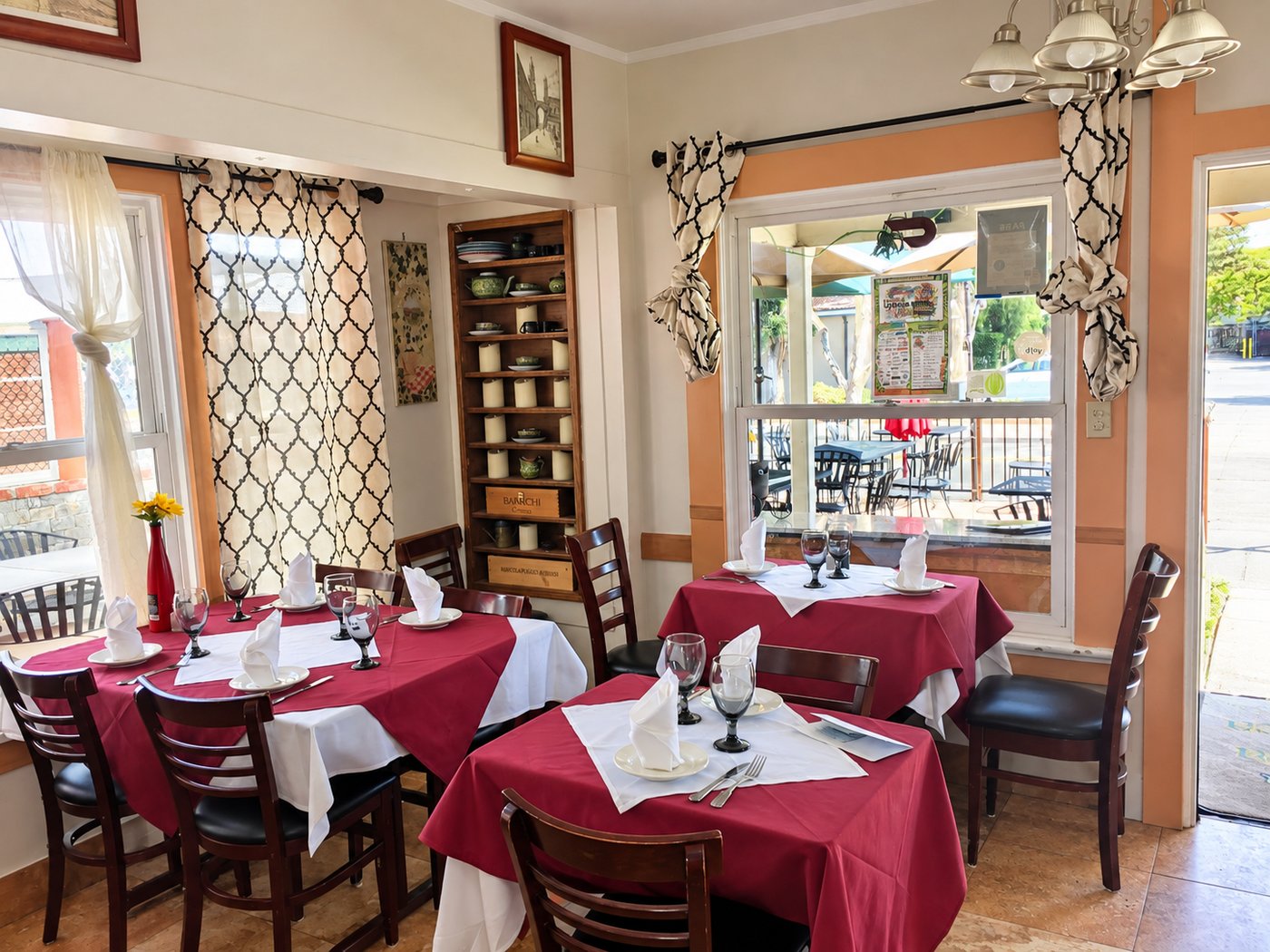Sicilia In Bocca dining room with burgundy tablecloths and tables beside the windows